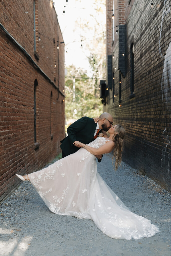 Bride and groom kissing in a string lit alley in Downtown Decatur, Georgia.