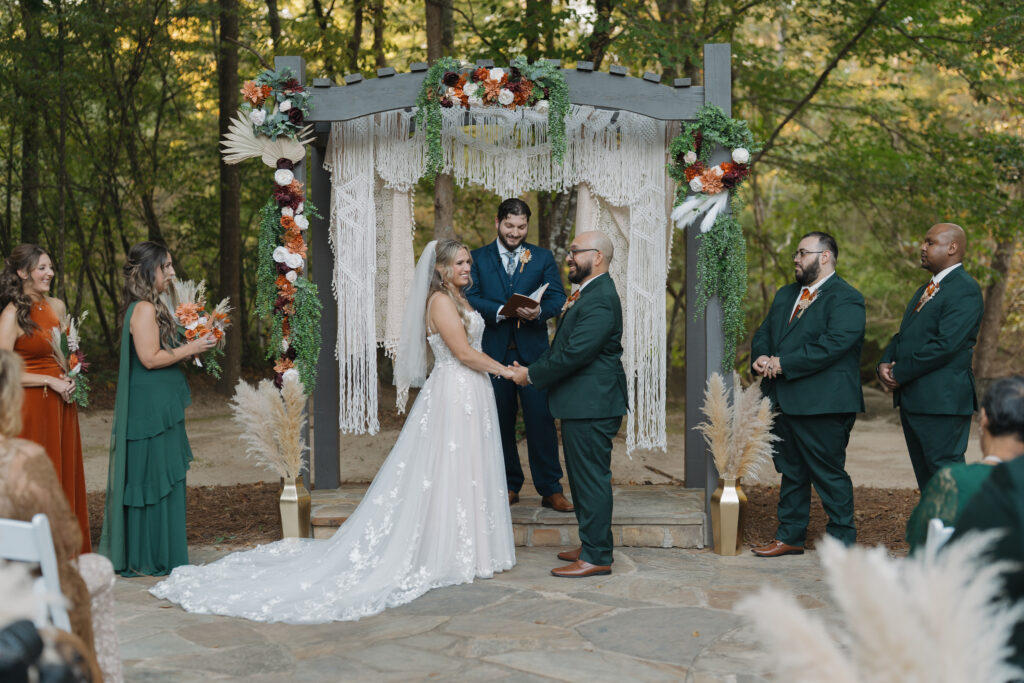 Bride and groom at ceremony at Vecoma at the Yellow River near Stone Mountain, smiling and holding hands