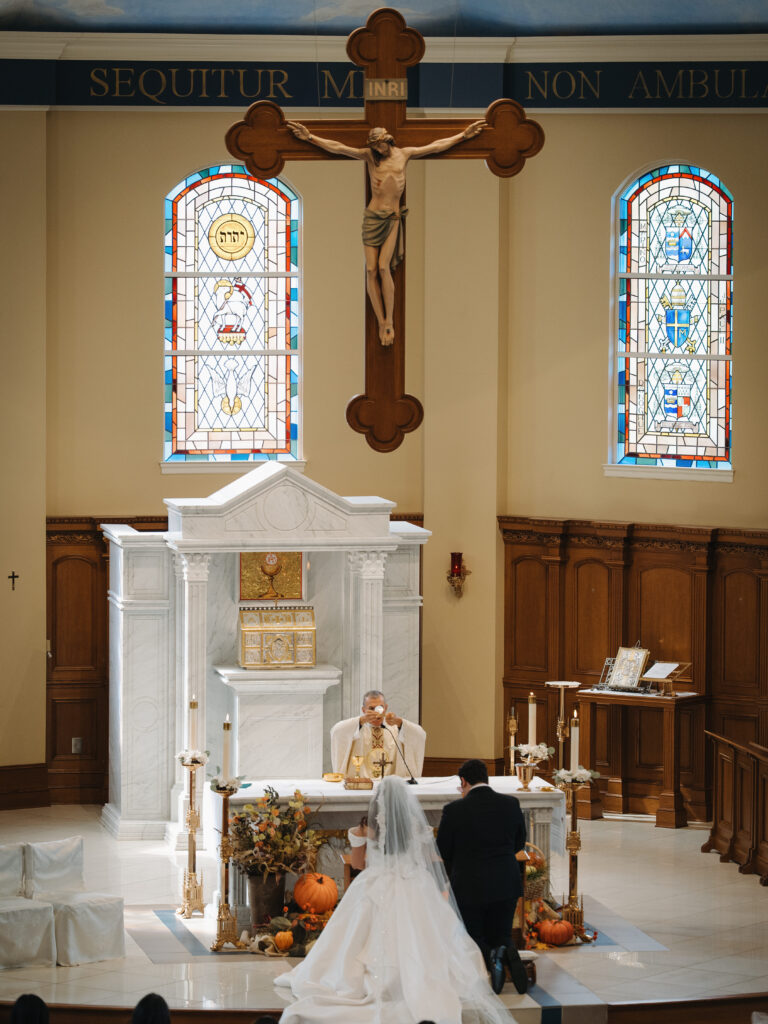 Bride and Groom kneeling at the alter in front of Eucharist at St.Benedict Catholic Church in John's Creek, Georgia