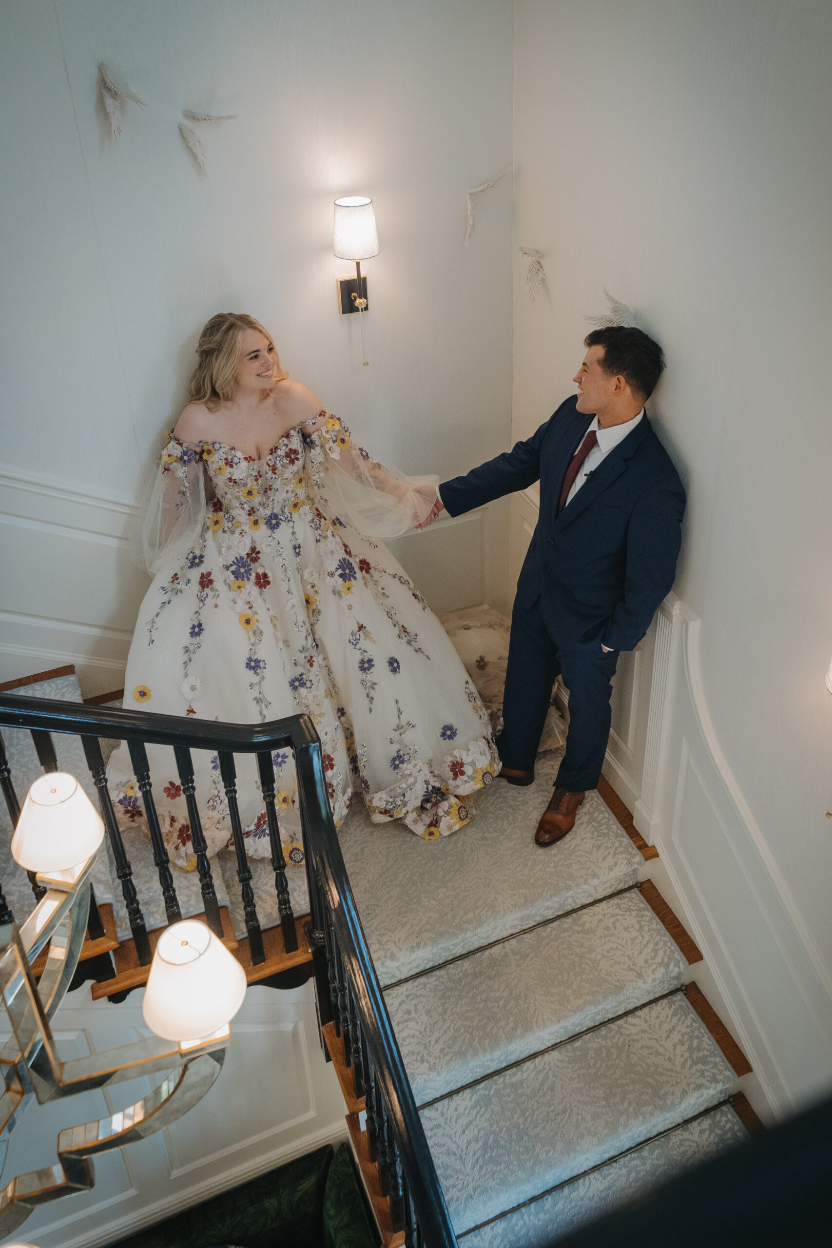 Bride and groom holding hands on staircase at The Meadowlands at the Darien Community Association. 