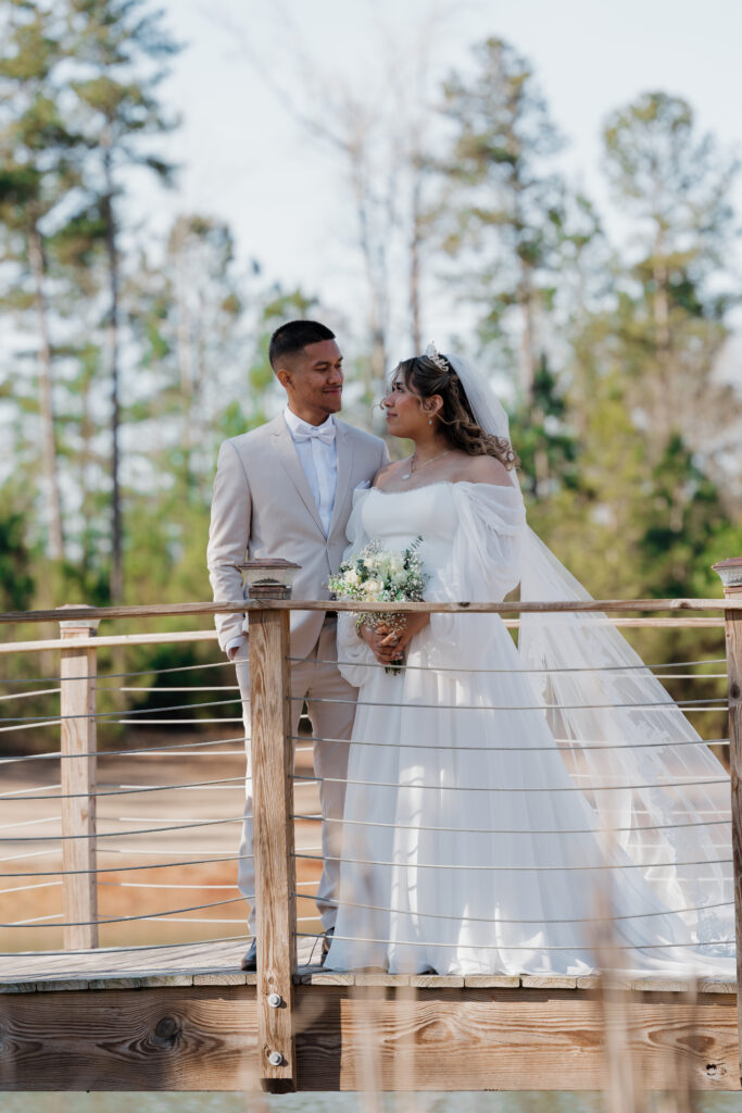 Wedding photo of bride and groom posing on the bridge at Mystic Acres wedding venue in Griffin, GA.