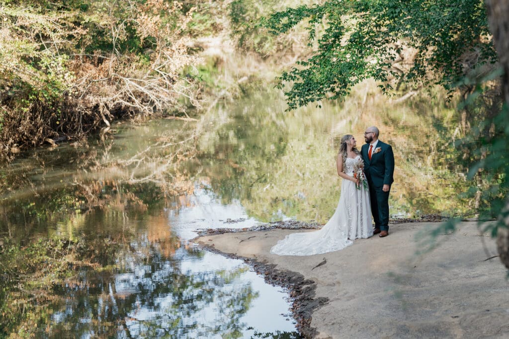 Bride and Groom standing together next to the river at Vecoma at the yellow river, in Snellville Georgia.